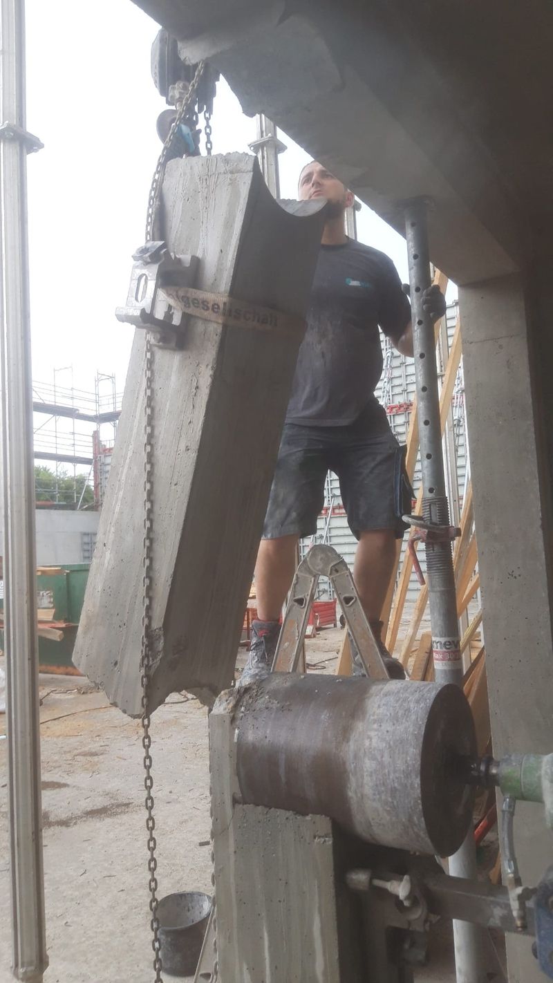 Mitarbeiter beim Absenken eines gebohrten Betonkerns mit Kette und Hebevorrichtung
